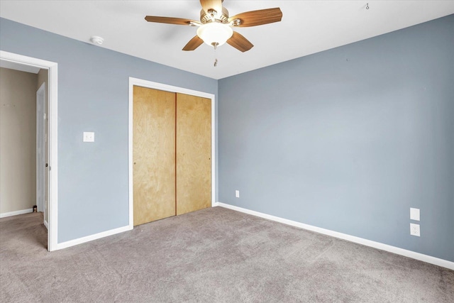 unfurnished bedroom featuring a ceiling fan, a closet, light colored carpet, and baseboards