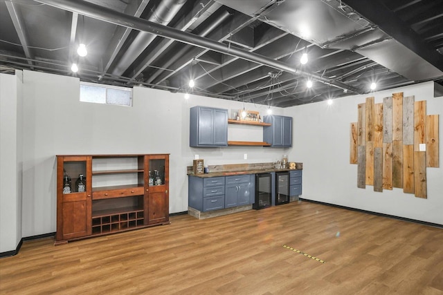 below grade area featuring light wood-style floors, baseboards, and bar area