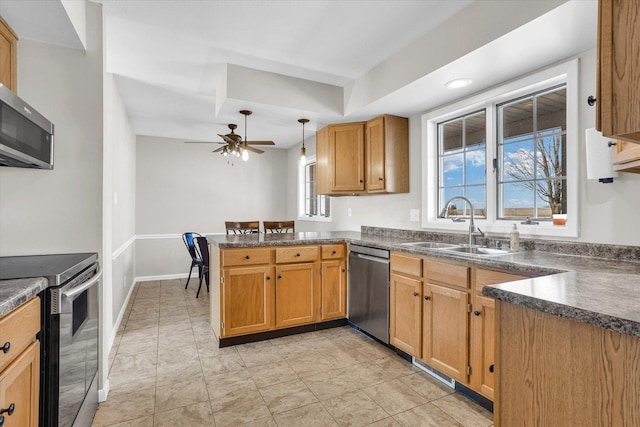 kitchen featuring dark countertops, a peninsula, hanging light fixtures, stainless steel appliances, and a sink