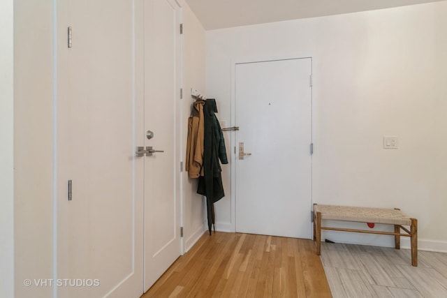 doorway with light wood finished floors and baseboards