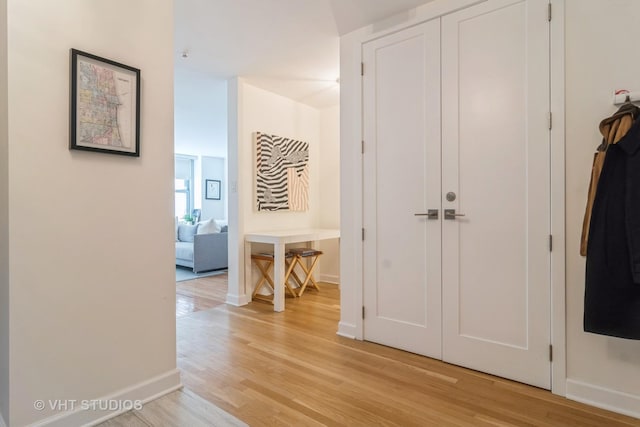 hall with baseboards and light wood-style floors