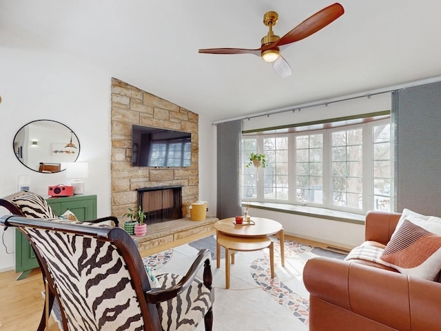 living area with lofted ceiling, a fireplace, baseboards, and a ceiling fan