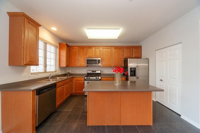 kitchen with sink, dark tile patterned flooring, stainless steel appliances, and a center island