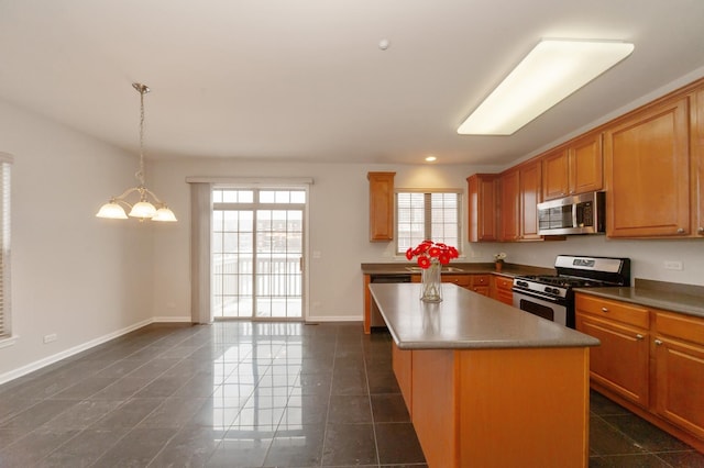 kitchen with appliances with stainless steel finishes, a center island, a healthy amount of sunlight, and pendant lighting