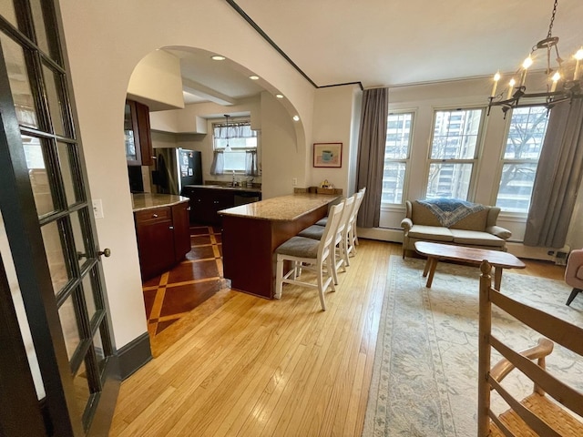 interior space featuring light wood-type flooring, arched walkways, and a chandelier