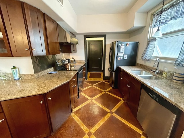 kitchen with appliances with stainless steel finishes, a sink, decorative light fixtures, and light stone countertops