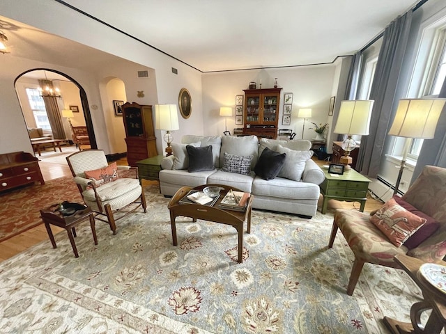 living room with a baseboard radiator, visible vents, and arched walkways