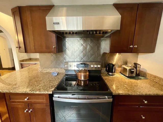 kitchen with light stone countertops, electric stove, backsplash, and extractor fan