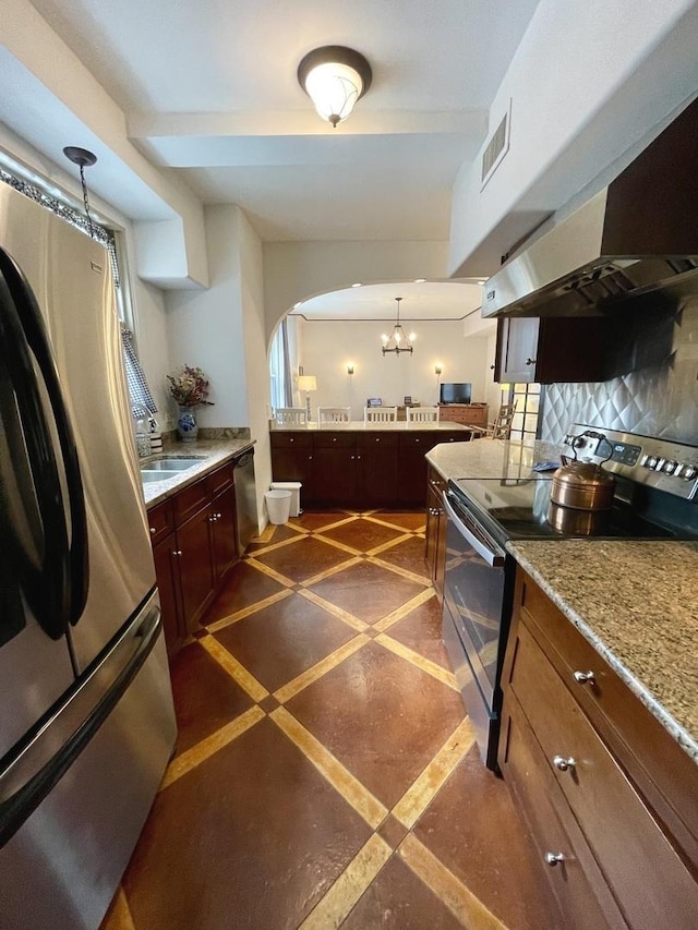 kitchen with arched walkways, decorative backsplash, appliances with stainless steel finishes, a sink, and under cabinet range hood