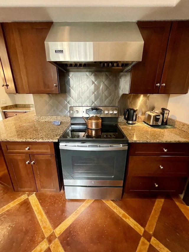 kitchen featuring stainless steel range with electric stovetop, light stone counters, extractor fan, and backsplash