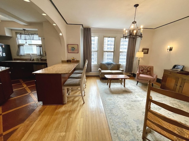 interior space with arched walkways, plenty of natural light, a chandelier, and light wood-style flooring