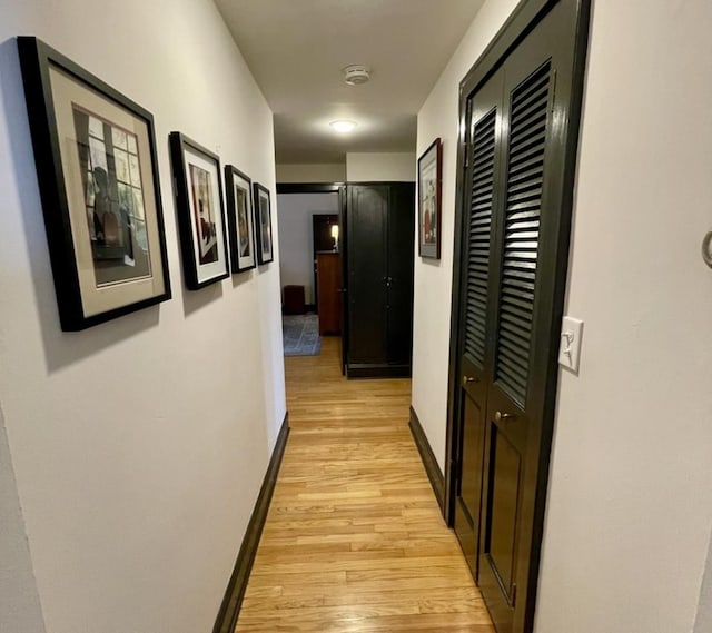 corridor featuring light wood-style flooring and baseboards