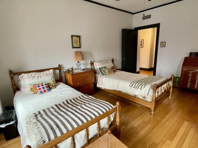 bedroom featuring ornamental molding, hardwood / wood-style floors, and visible vents