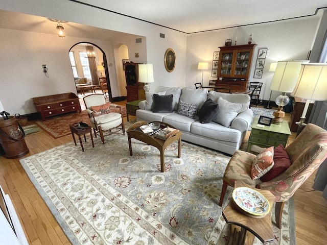 living area featuring hardwood / wood-style flooring, visible vents, and arched walkways