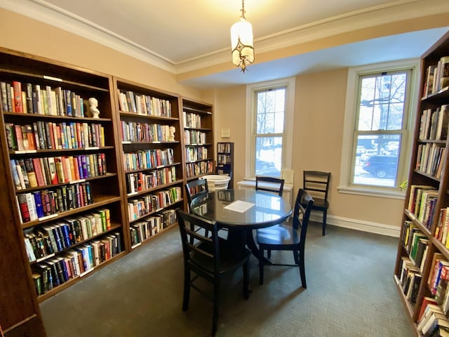 dining space featuring ornamental molding, dark carpet, and baseboards