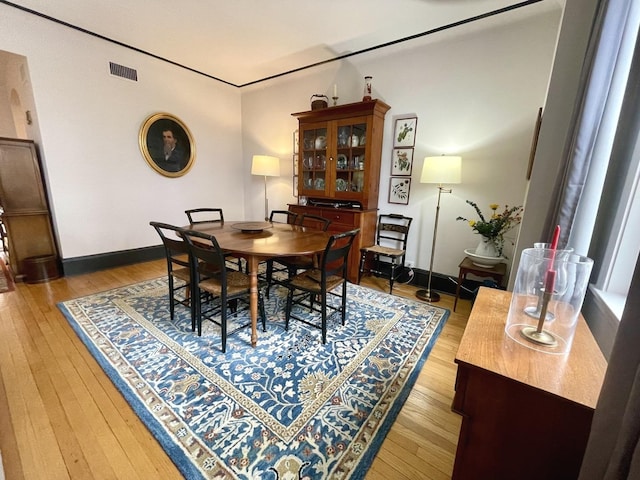 dining room with light wood-type flooring, visible vents, and baseboards