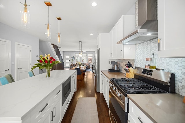 kitchen featuring dark wood-style floors, wall chimney exhaust hood, open floor plan, stainless steel appliances, and backsplash