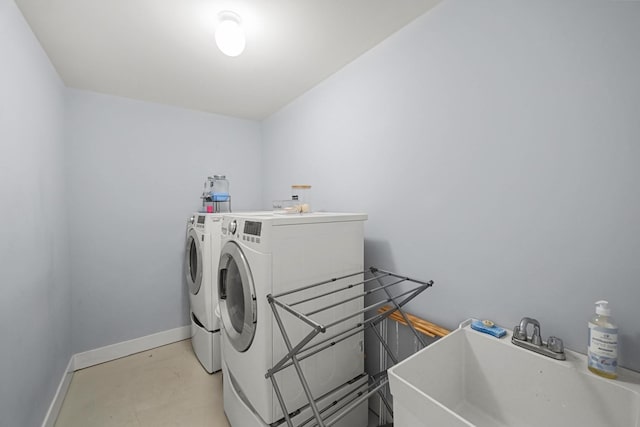 laundry room with laundry area, baseboards, a sink, and washing machine and clothes dryer