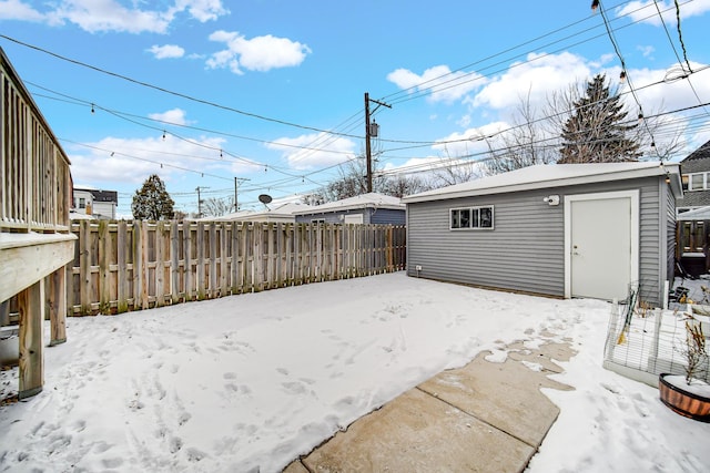 snowy yard with an outbuilding and fence