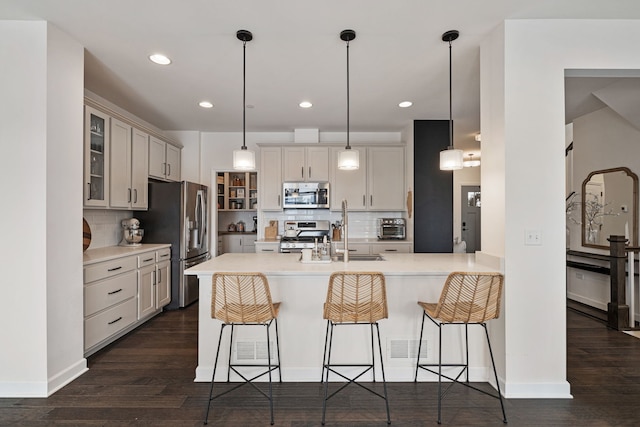 kitchen featuring appliances with stainless steel finishes, a kitchen breakfast bar, pendant lighting, dark hardwood / wood-style flooring, and sink