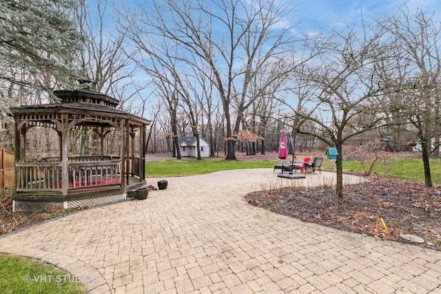 view of property's community with a patio, an outdoor structure, a gazebo, driveway, and a wooden deck