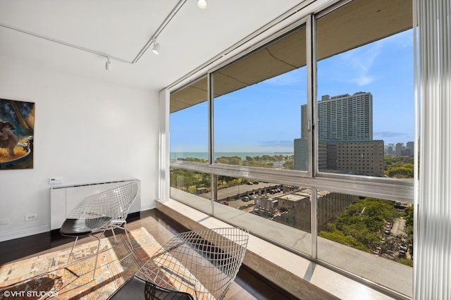 sunroom / solarium with rail lighting, a healthy amount of sunlight, and a water view