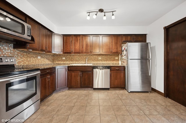 kitchen with sink, tasteful backsplash, light tile patterned floors, stainless steel appliances, and light stone countertops