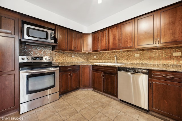 kitchen featuring appliances with stainless steel finishes, tasteful backsplash, sink, light tile patterned floors, and light stone countertops