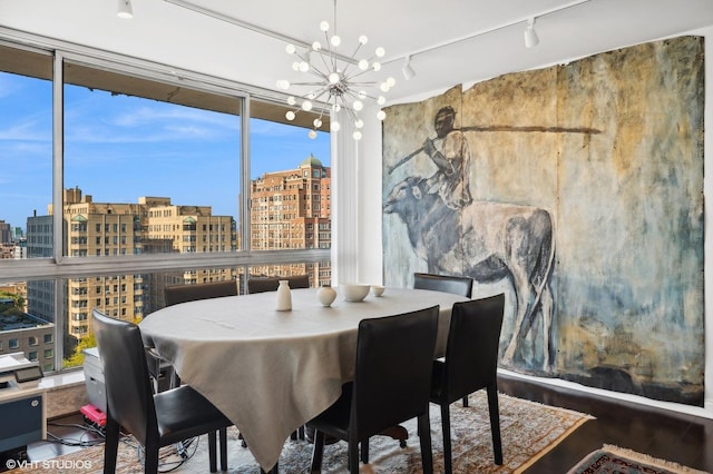 dining space with expansive windows, track lighting, and a chandelier