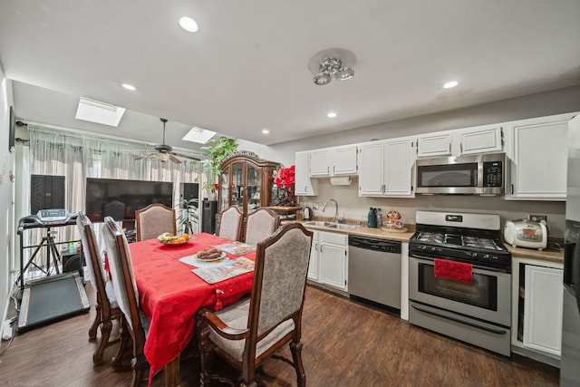 kitchen with sink, dark wood-type flooring, appliances with stainless steel finishes, a skylight, and white cabinets