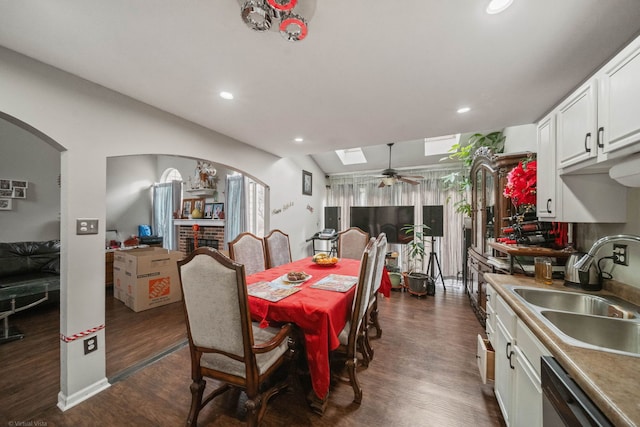 dining room with ceiling fan, dark hardwood / wood-style floors, a skylight, and sink