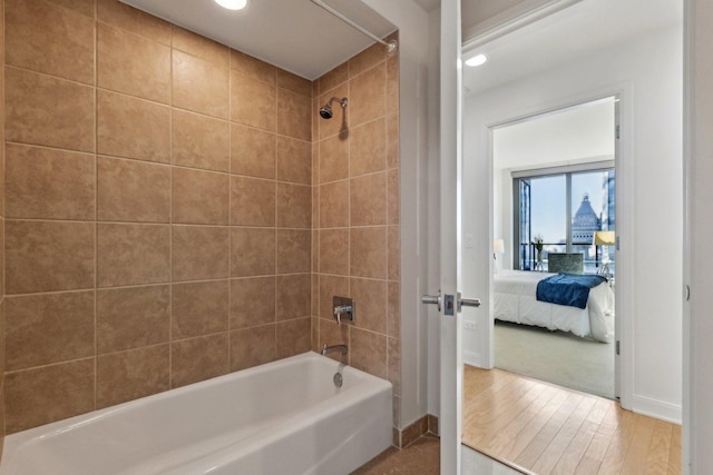 bathroom with hardwood / wood-style flooring and tiled shower / bath