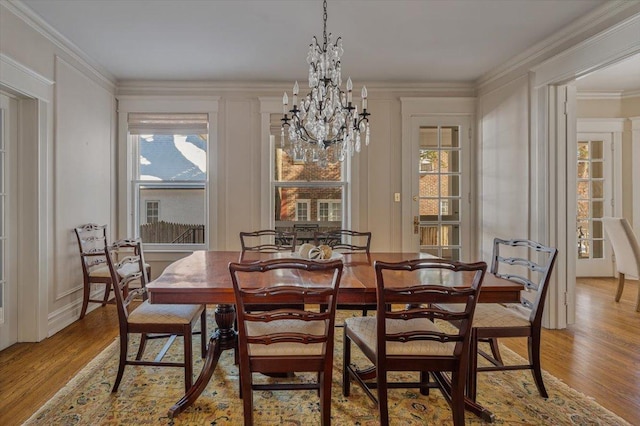 dining area featuring a notable chandelier, light wood-type flooring, and crown molding