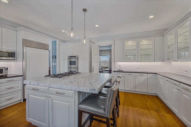 kitchen with a breakfast bar, white cabinetry, stainless steel appliances, and wood finished floors