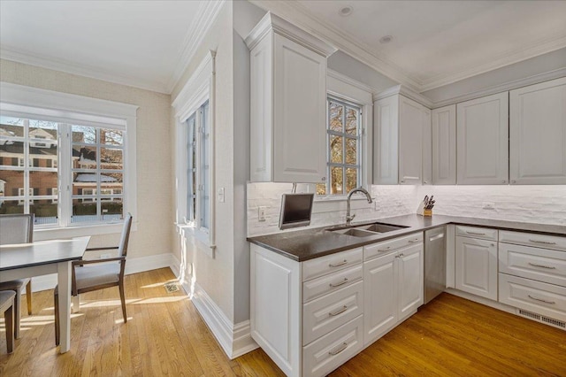 kitchen with light wood-style floors, a sink, white cabinetry, and crown molding