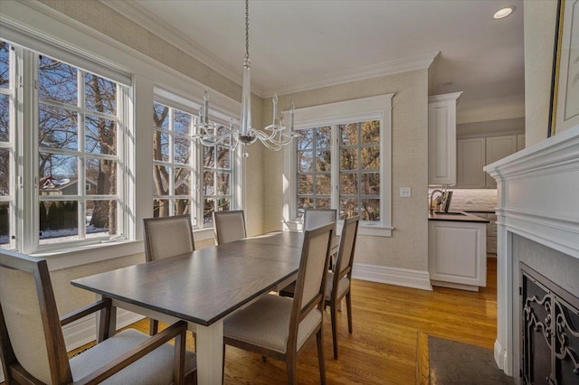 dining room featuring crown molding, light wood-style flooring, baseboards, and an inviting chandelier