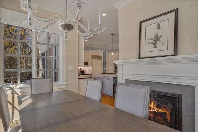 unfurnished dining area featuring a warm lit fireplace, plenty of natural light, ornamental molding, and light wood-style floors