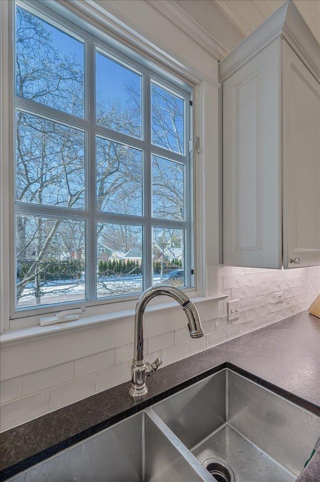 details with crown molding, dark countertops, backsplash, white cabinets, and a sink