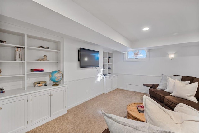 living room with built in shelves, recessed lighting, light carpet, and baseboards