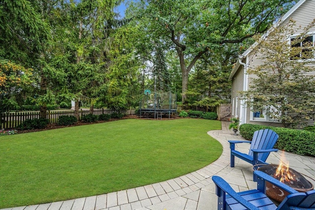 view of yard featuring fence private yard, a patio area, an outdoor fire pit, and a trampoline