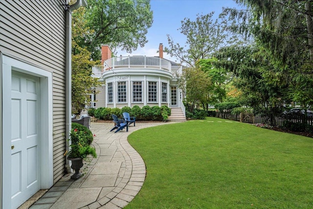 back of property with a patio area, a lawn, a balcony, and fence