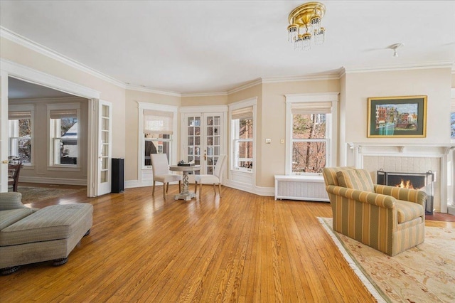 sitting room featuring a tile fireplace, ornamental molding, french doors, light wood-type flooring, and radiator