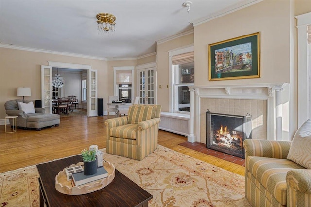 living room with ornamental molding, radiator, a tiled fireplace, and wood finished floors