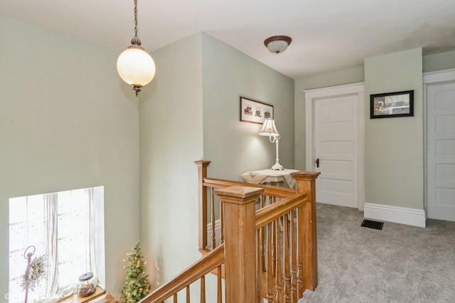 hallway with carpet, an upstairs landing, and baseboards