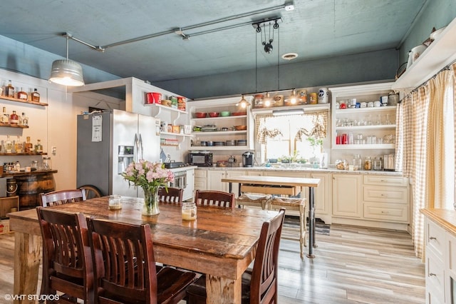 dining space featuring bar, plenty of natural light, and light wood finished floors