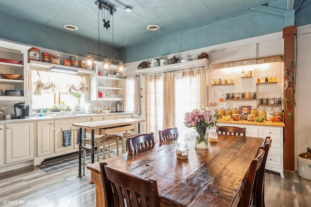 dining room featuring indoor wet bar, light wood-style floors, and visible vents