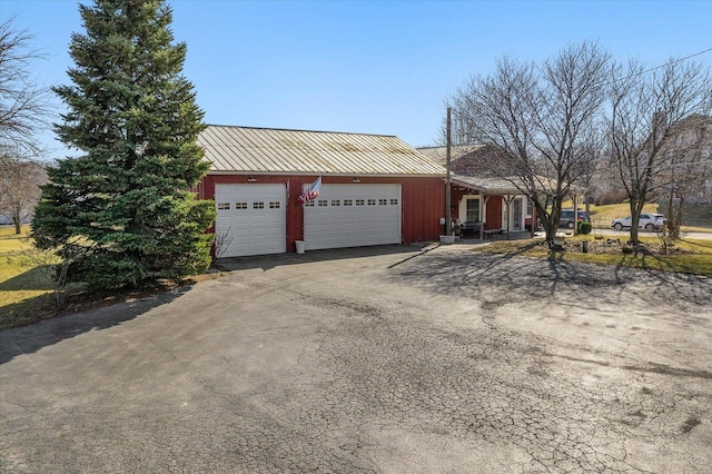 view of front of property with a standing seam roof, metal roof, aphalt driveway, and a garage
