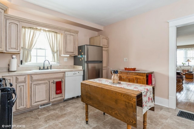 kitchen with range with gas cooktop, freestanding refrigerator, a sink, light countertops, and dishwasher