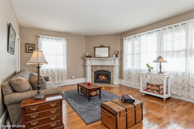 living room featuring a tile fireplace, baseboards, and hardwood / wood-style flooring
