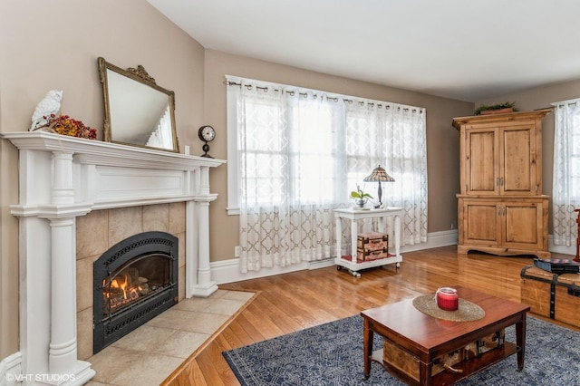 living room with light wood-style floors, baseboards, and a tile fireplace